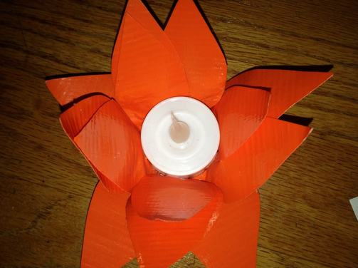 Repeat all around the flower, layering the petals where you like in order to create a lotus-like figure. You may have to bend the duct tape toward the outside of the candle to prevent the petals from just sticking straight up, but it should bend willingly. With that, the lotus is done!