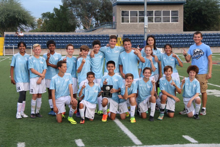 The soccer team poses with their first place plaque.