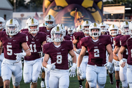 High school football players emerging onto the field.