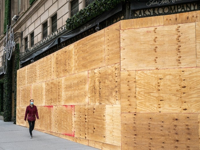 A woman walking past a street of boarded up shops.