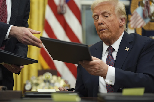 President Trump receiving an executive order to sign.