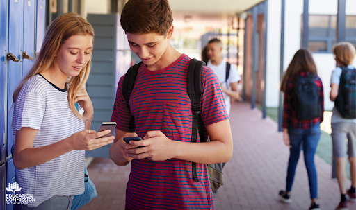 Picture of two high school students on their phones near lockers.